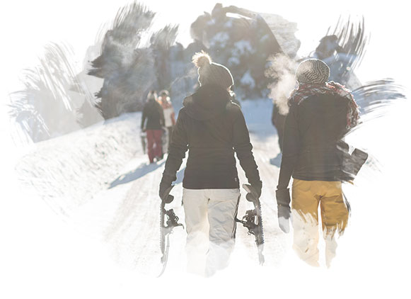 Family snowshowing in a sun-lit forest, covered in beautiful white snow.